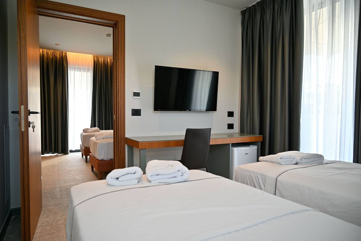 Ett hotellrum med två sängar, ett skrivbord, en TV och en minibar.
