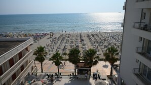 A beach with numerous umbrellas and palm trees, a clear sky, and a view of the sea. - Adria Palace Hotel (Rrashbull)
