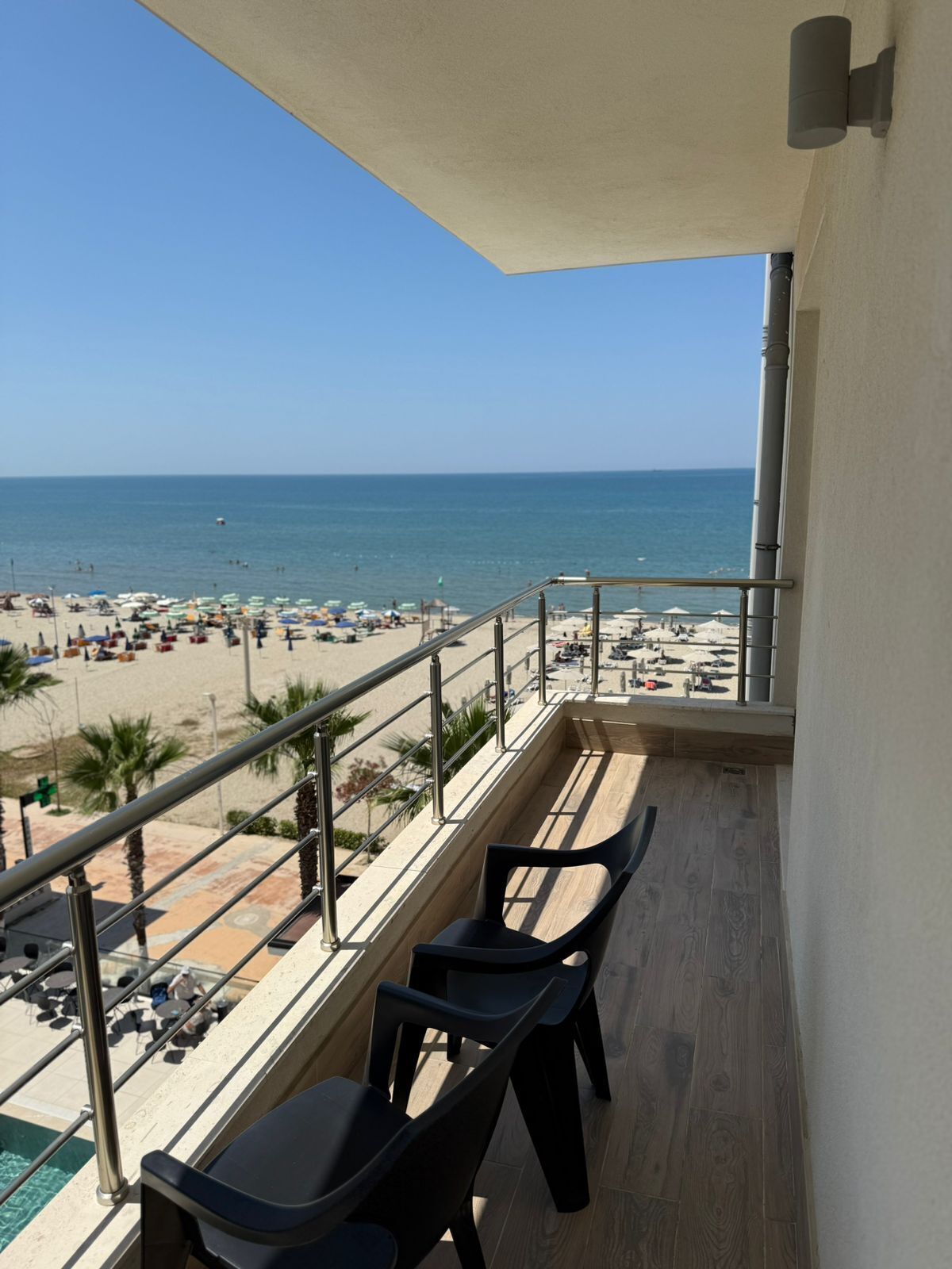 Un balcó amb vista a la platja, una piscina i una barana.