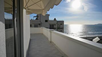 Un balcón con vista al mar, un edificio blanco y un cielo despejado.