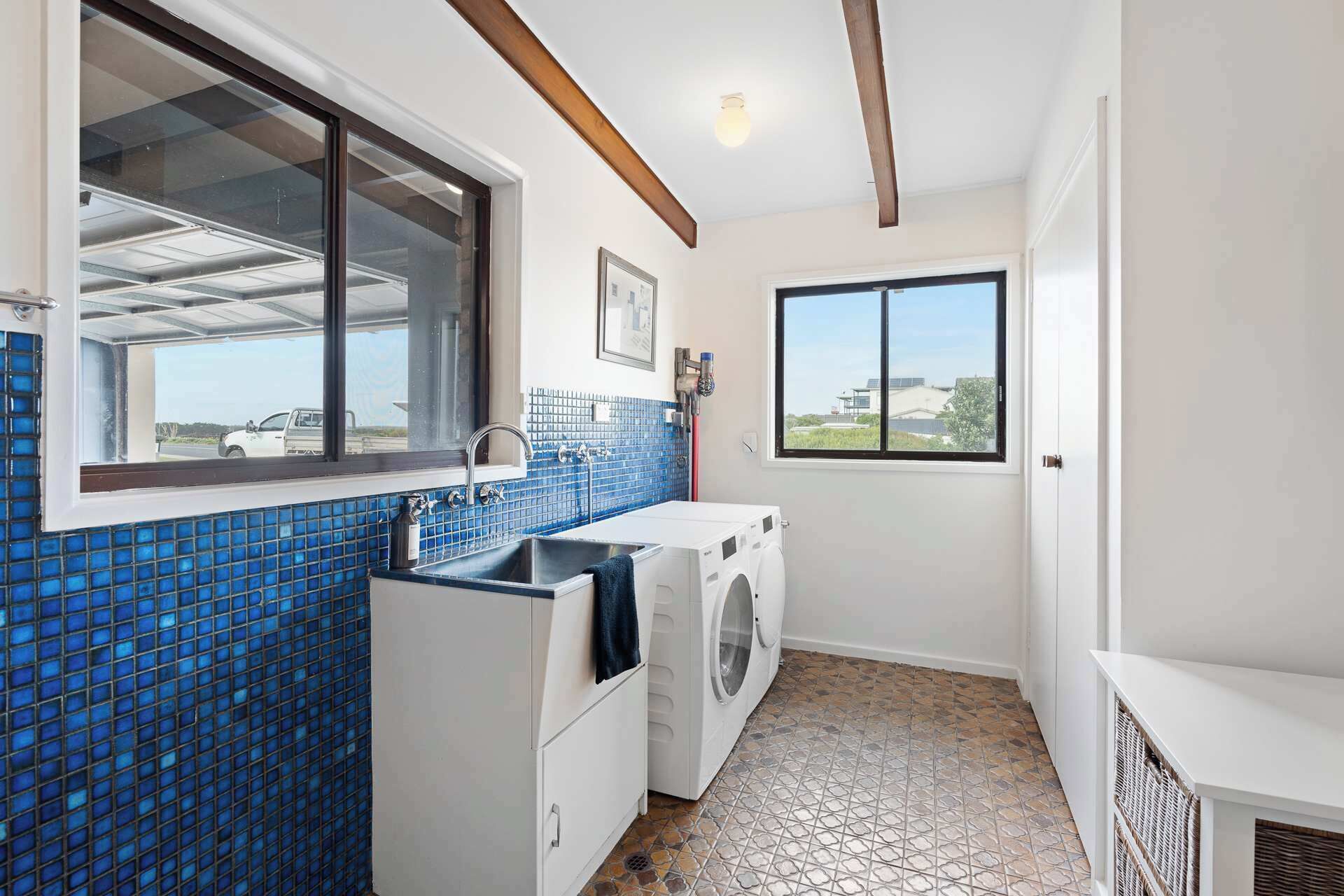 A compact laundry room with a washing machine, a sink, and a window providing a view of the outside.