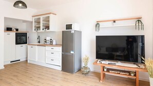 A modern kitchen with white cabinets, a stainless steel refrigerator, and a wooden dining table. - Comfortable 2-Bedroom Family Apartment in the small, quiet street. (Orebic)