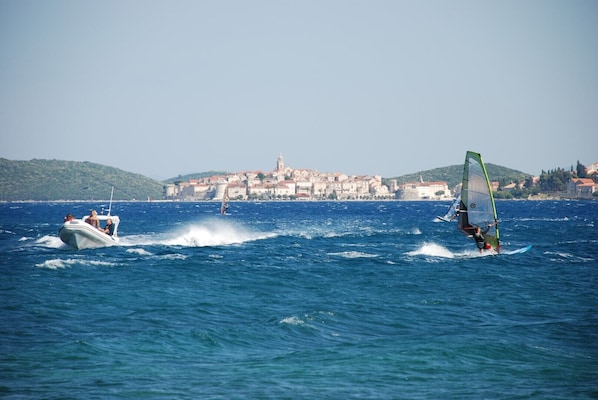 A coastal scene with a boat and a person windsurfing.
