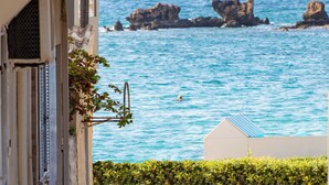 A coastal view from a building with a paved walkway leading to the sea, featuring rocky outcrops and a clear sky. - Casa Gardenia -modern apartment next to the beach and near old town (Chania)