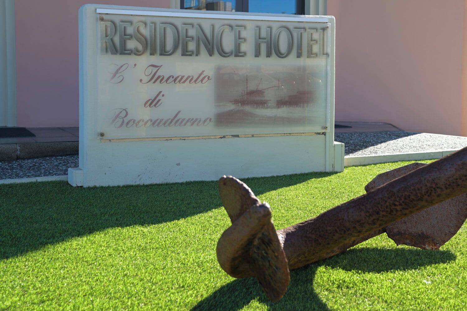 A sign for the Residence Hotel with a rustic stone sculpture in front.