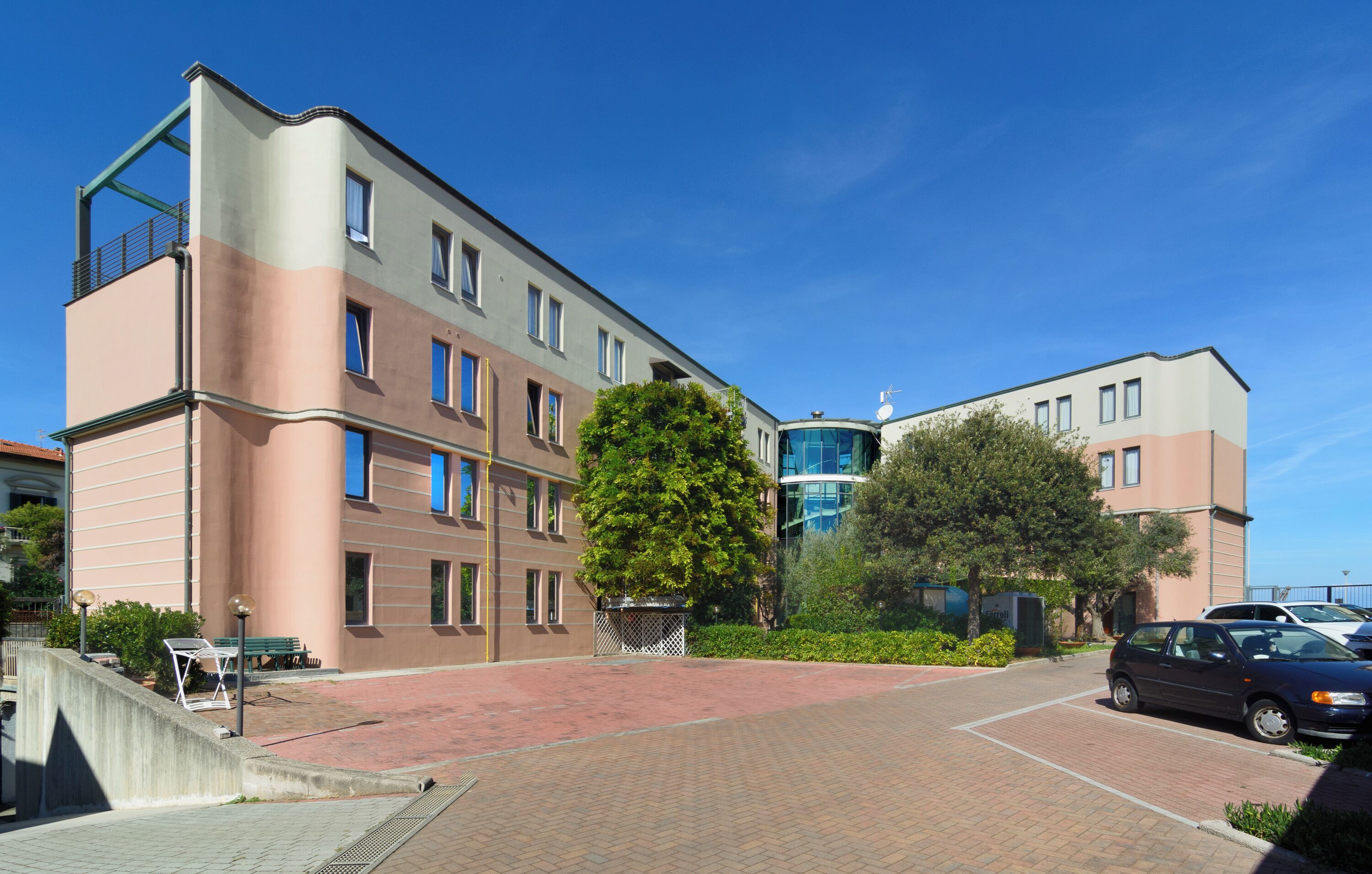A multi-story building with a flat roof, large windows, and a brick-paved courtyard.