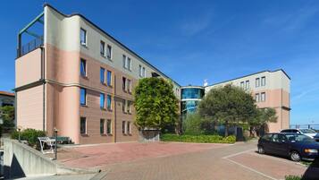 A multi-story building with a flat roof, large windows, and a brick-paved courtyard.