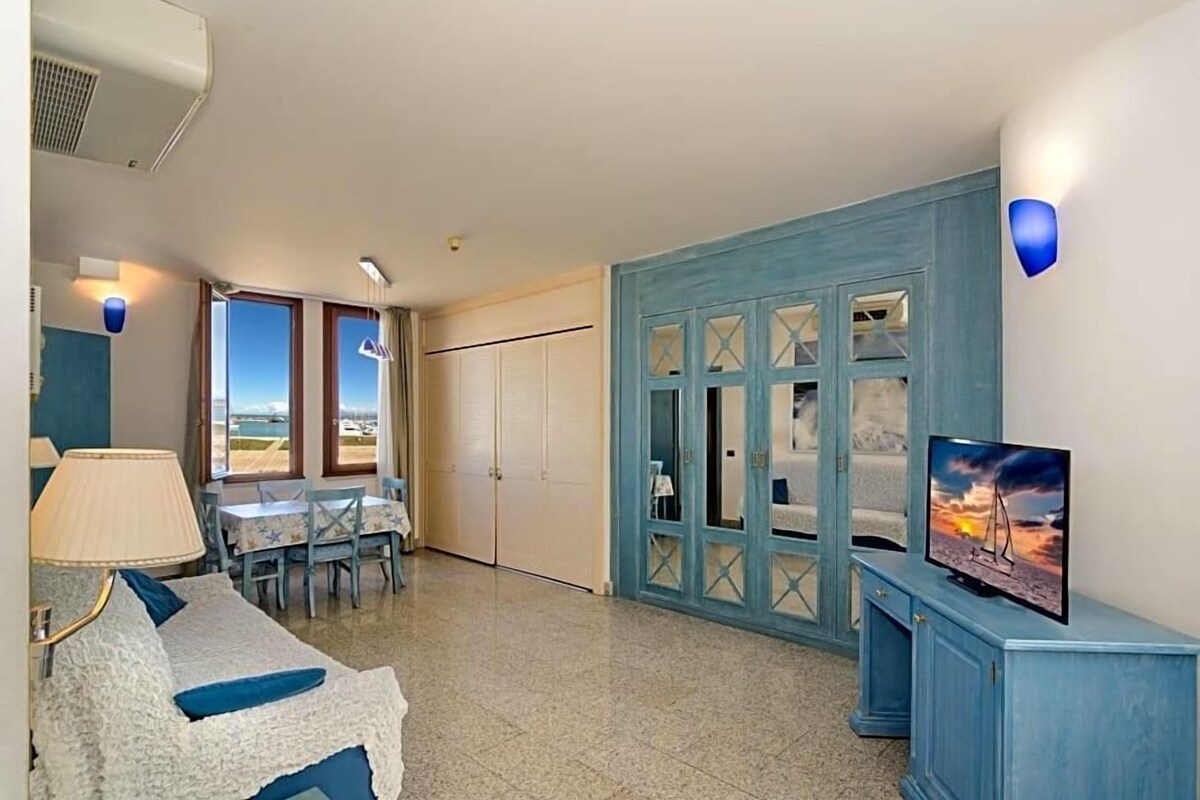 A room with a TV, a dining area, and a view of the outdoors.