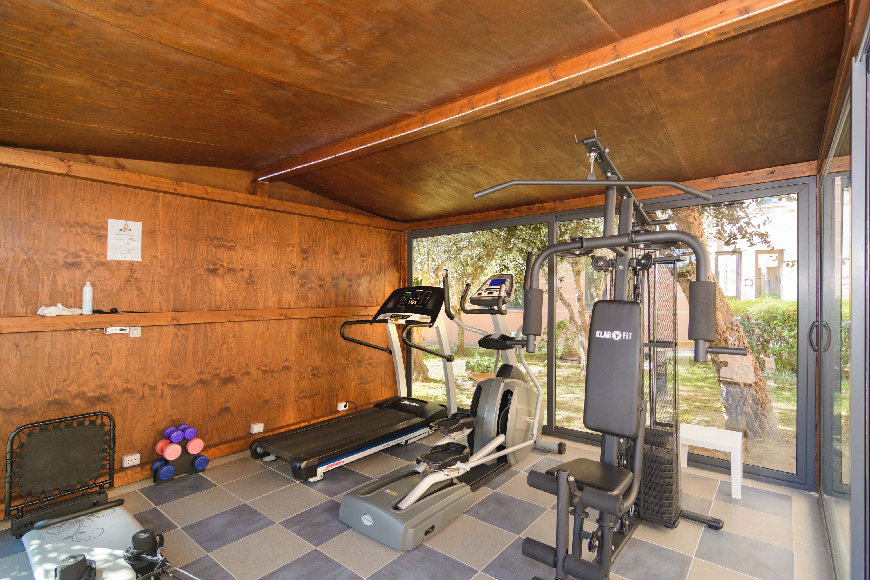 Un espacio cubierto para gimnasio con cinta de correr, elíptica y máquina de pesas.