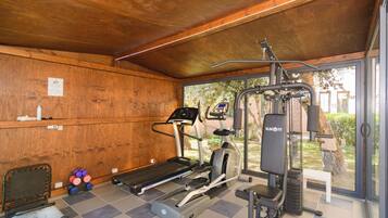 Un espacio cubierto para gimnasio con cinta de correr, elíptica y máquina de pesas.