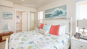 A bedroom with a bed, a nightstand, a ceiling fan, a painting of a wave, and a starfish decoration. - Steps to Surf & Sand | Beachfront Oasis + Pier Walk (Pismo Beach)