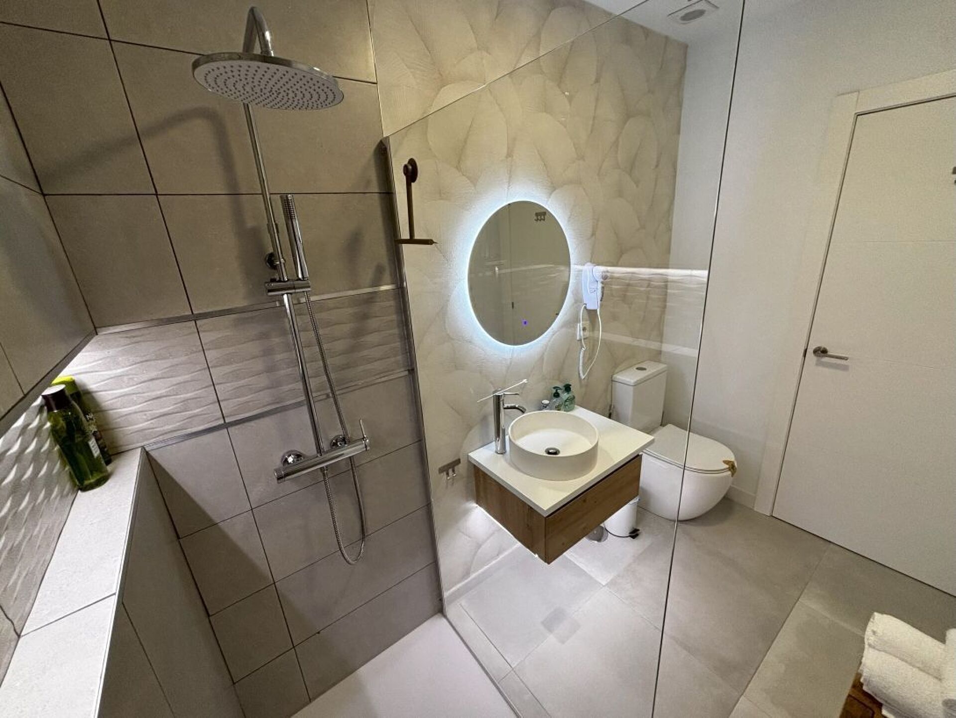A modern bathroom with a shower, sink, toilet, and a mirror.