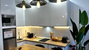 Una cocina moderna con microondas, cafetera, tostadora y una mesa de comedor de madera con un control remoto y un adorno.