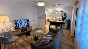 Una sala de estar moderna con televisor, sofá y comedor.