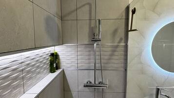 Un bagno moderno con doccia, lavandino e specchio.