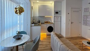 A modern kitchen with a microwave, washing machine, and a dining area with a round table and chairs. - PIO XII XXI - B - Bright, central, and cozy apartment. - Deluxe 1 bedroom apartment (Talavera de la Reina)