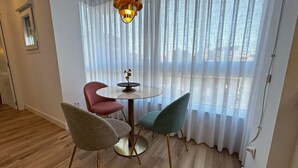 A room with a round table, two chairs, a hanging light fixture, and a window with sheer curtains. - PIO XII XXI - B - Bright, central, and cozy apartment. - Deluxe 1 bedroom apartment (Talavera de la Reina)