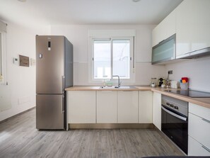 Una cocina moderna con refrigerador, horno y microondas integrados, un ventanal grande y un lavamanos.
