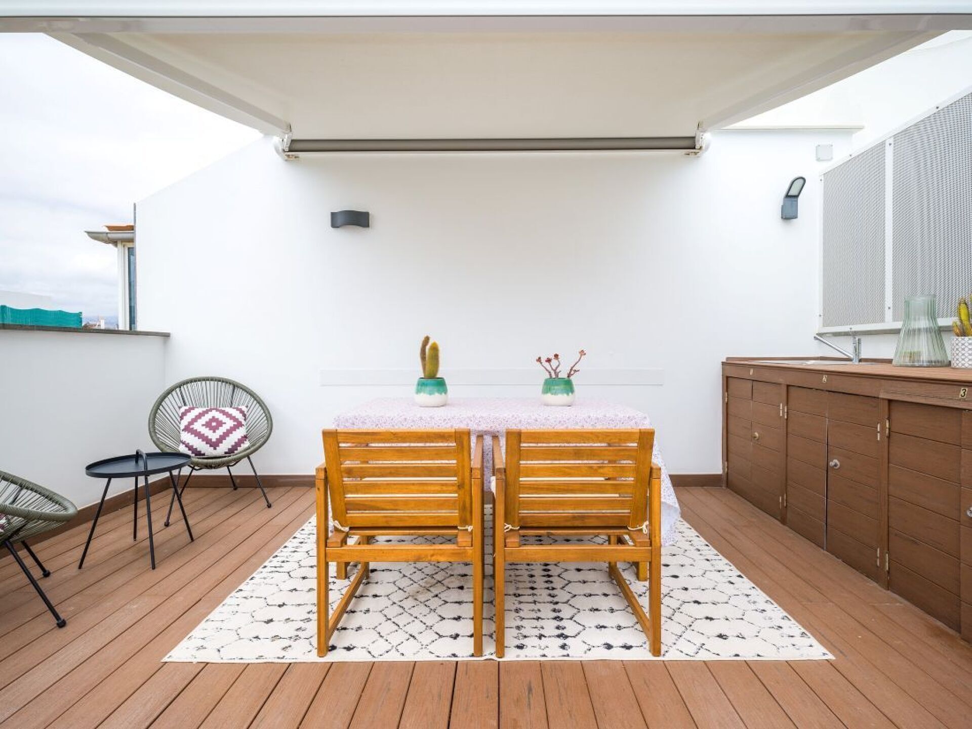 A patio with a table and chairs, a small cabinet, and a window with a view.