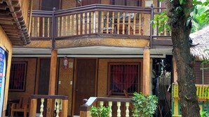 A traditional wooden building with a balcony, stone flooring, and potted plants. - morenos cottage  (Boracay Island)