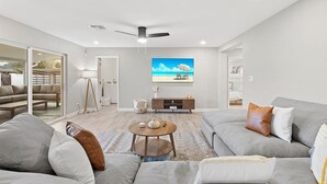 A modern living room with a large grey sofa, a coffee table, and a TV on the wall. - Solace | Pool, Hot Tub, Cabana, Fire Pit, Outdoor Living, Sleeps 22 | Old Town Scottsdale (Scottsdale)