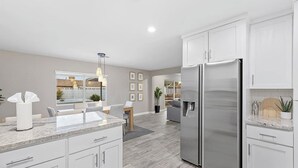 A modern kitchen with white cabinets, a stainless steel refrigerator, and a granite countertop. - Solace | Pool, Hot Tub, Cabana, Fire Pit, Outdoor Living, Sleeps 22 | Old Town Scottsdale (Scottsdale)