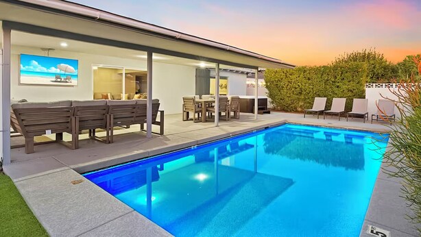 A modern outdoor pool area with a covered seating area, lounge chairs, and a dining table. - Solace | Pool, Hot Tub, Cabana, Fire Pit, Outdoor Living, Sleeps 22 | Old Town Scottsdale (Scottsdale)