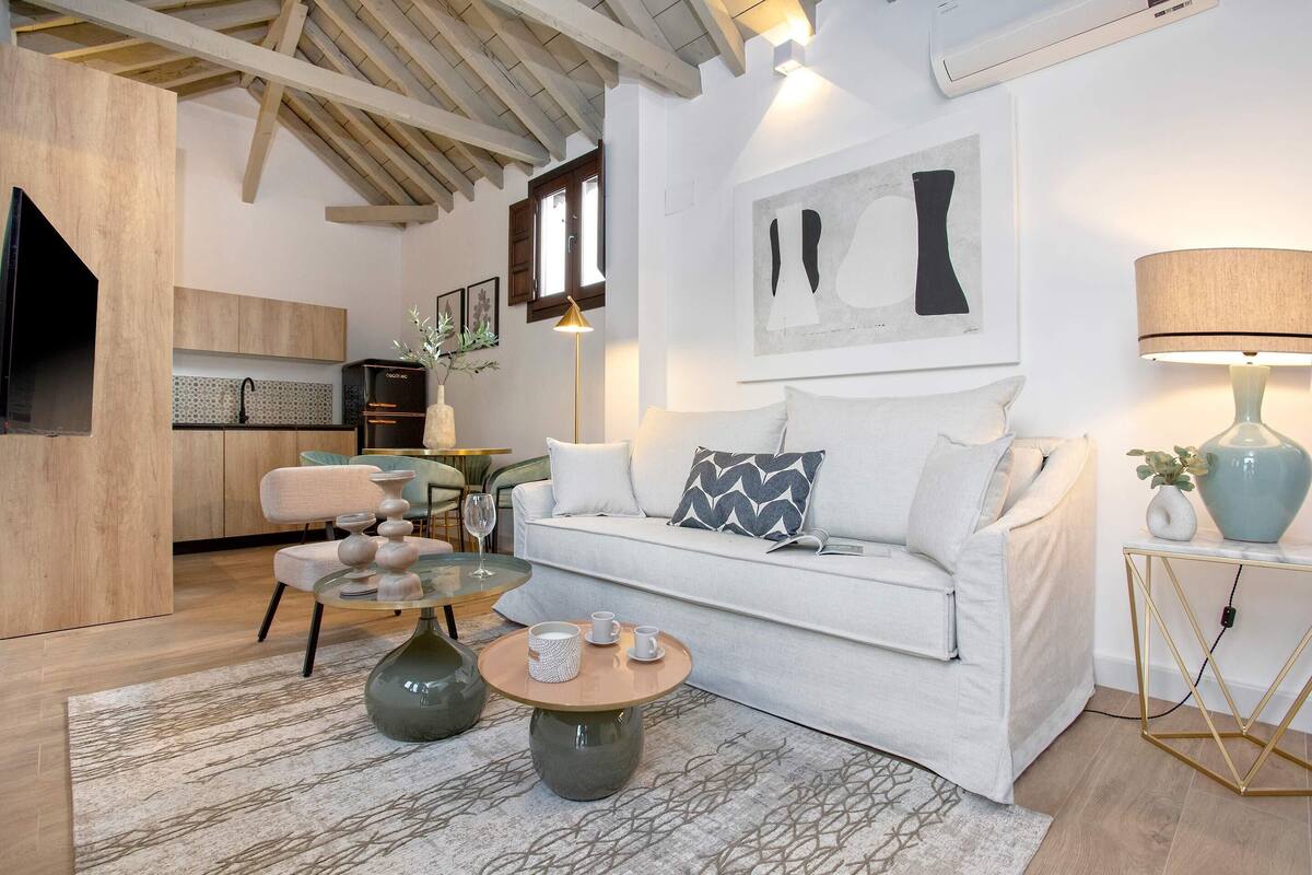 Ein modernes Wohnzimmer mit einem weißen Sofa, einem runden Couchtisch und einem Essbereich mit einem Glastisch und Stühlen.