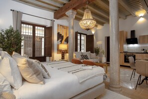 A bedroom with a large bed, a chandelier, and a view of the kitchen. - Genteel Home Horno Marina (Granada)
