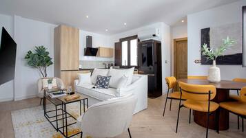 Un salon moderne avec un canapé blanc, une table basse et un coin repas avec des chaises jaunes.