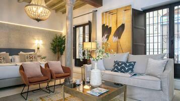 Een moderne woonkamer met een bank, fauteuils, een salontafel en een groot schilderij.