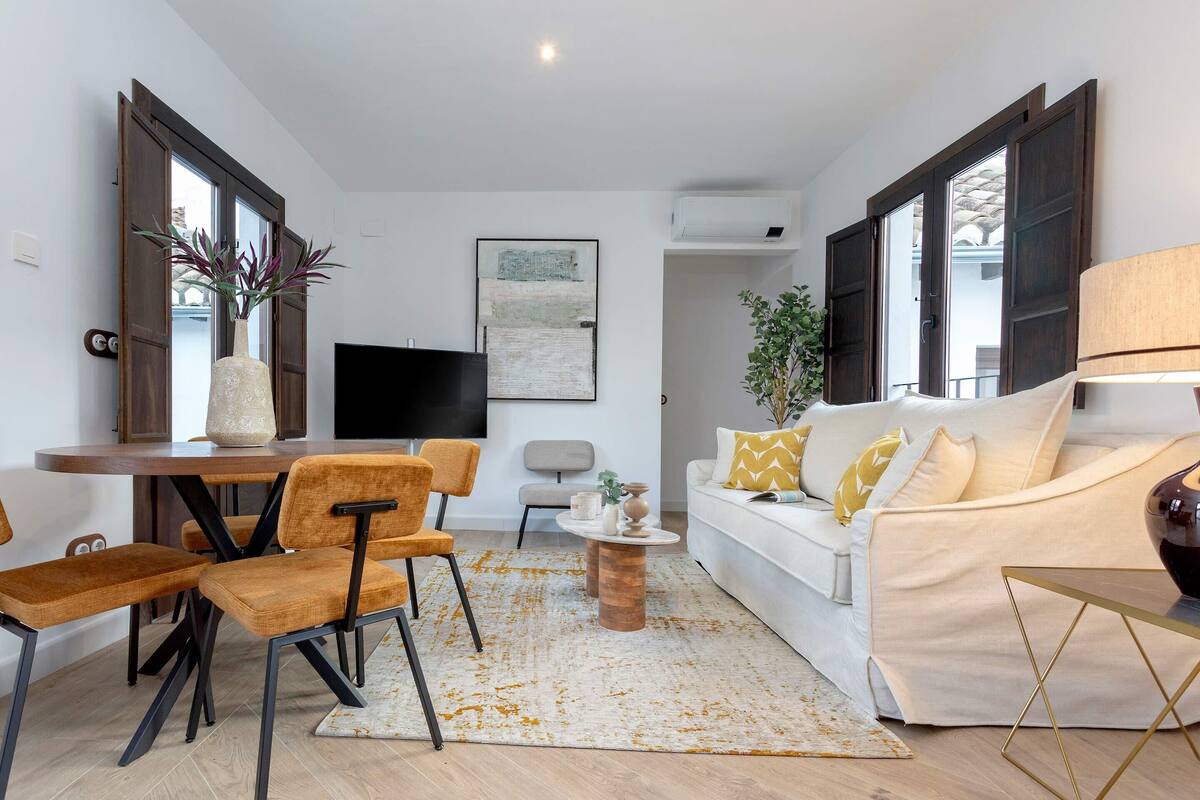 Ein modernes Wohnzimmer mit einem weißen Sofa, orangefarbenen Sesseln, einem Couchtisch und einem Fernseher.