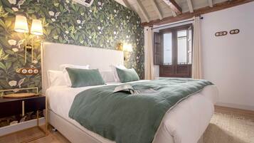 A bedroom with a bed, bedside lamps, a nightstand, and a window with curtains.