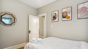 Un dormitori amb un llit, una porta i tres quadres al mur.