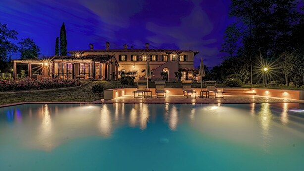 A large house with a swimming pool, outdoor seating, and a well-lit patio area. - Il Cerreto 11 Emma Villas (Pontedera)