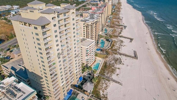 Un hotel costero con varios edificios altos, una playa de arena y vista al océano.