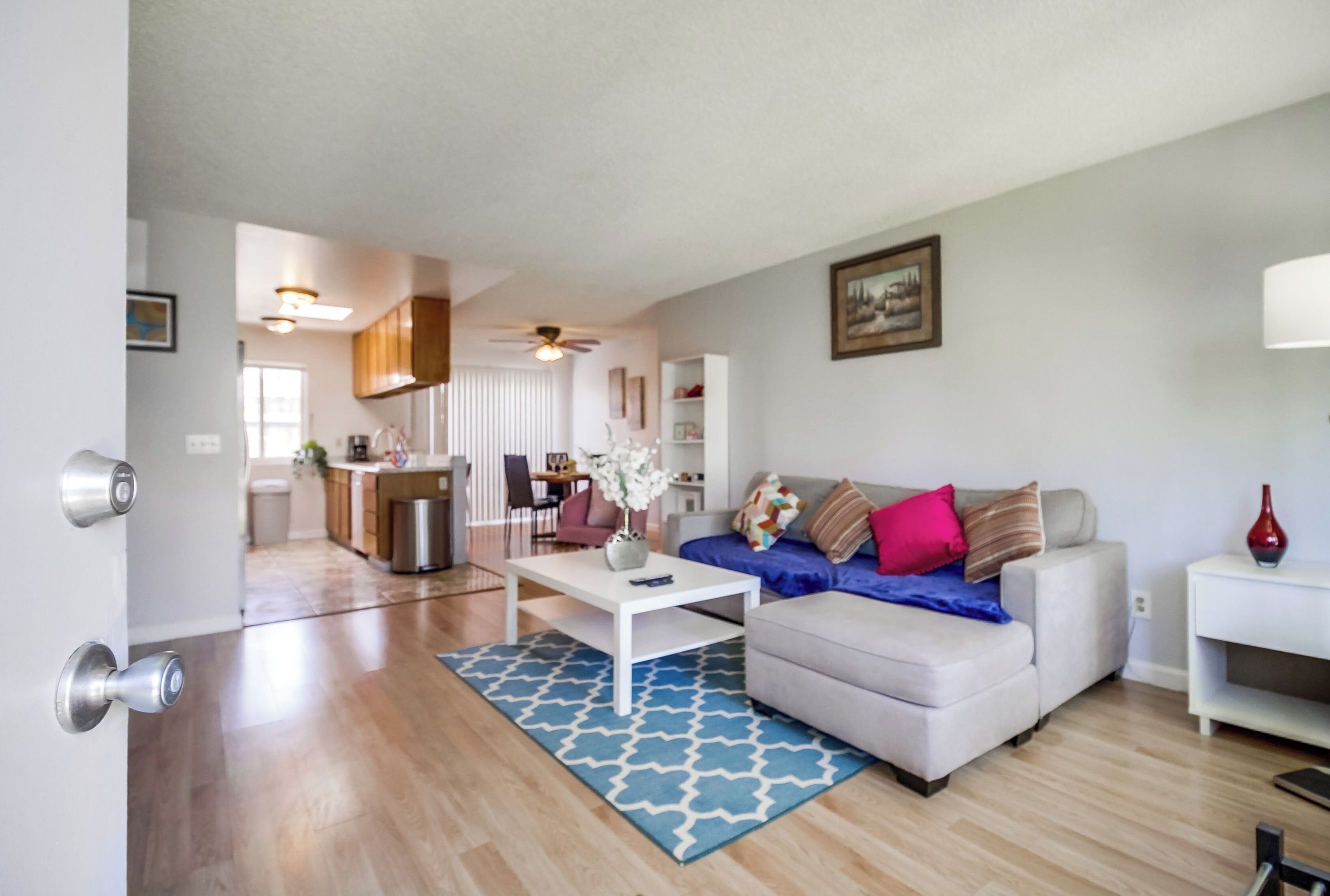 A modern living room with a sofa, coffee table, and a dining area in the background.