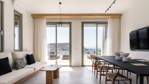 A modern living room with a sofa, dining table, and chairs, large windows with a view of the city.