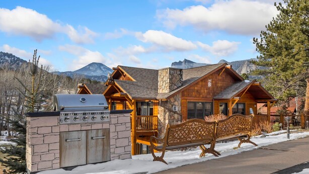 A lodge with a stone grill, wooden exterior, and a bench along the walkway. - Cozy Mountain Retreat • Near RMNP & Downtown (Estes Park)