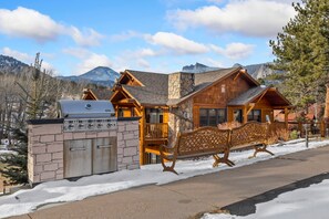 A lodge with a stone grill, wooden exterior, and a bench along the walkway. - Cozy Mountain Retreat • Near RMNP & Downtown (Estes Park)