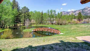 A wooden bridge over a pond surrounded by trees and mountains. - Cozy Mountain Retreat • Near RMNP & Downtown (Estes Park)