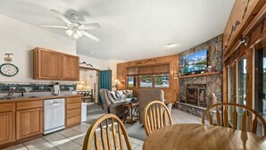 A kitchen with wooden cabinets, a dishwasher, and a dining area with a table and chairs. - Cozy Mountain Retreat • Near RMNP & Downtown (Estes Park)