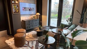 A modern living room with a sofa, two round tables, a TV, and various plants. - The Depot in Bath (Bath)