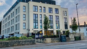 A multi-story building with a flat roof, large windows, and a sign indicating it is a student hostel. - The Depot in Bath (Bath)
