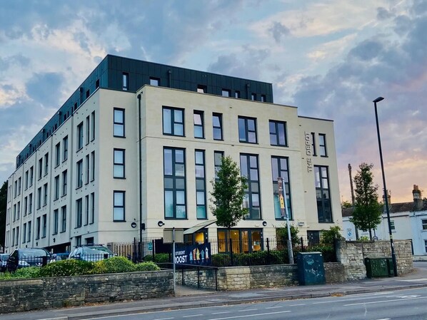 A multi-story building with a flat roof, large windows, and a sign indicating it is a student hostel. - The Depot in Bath (Bath)