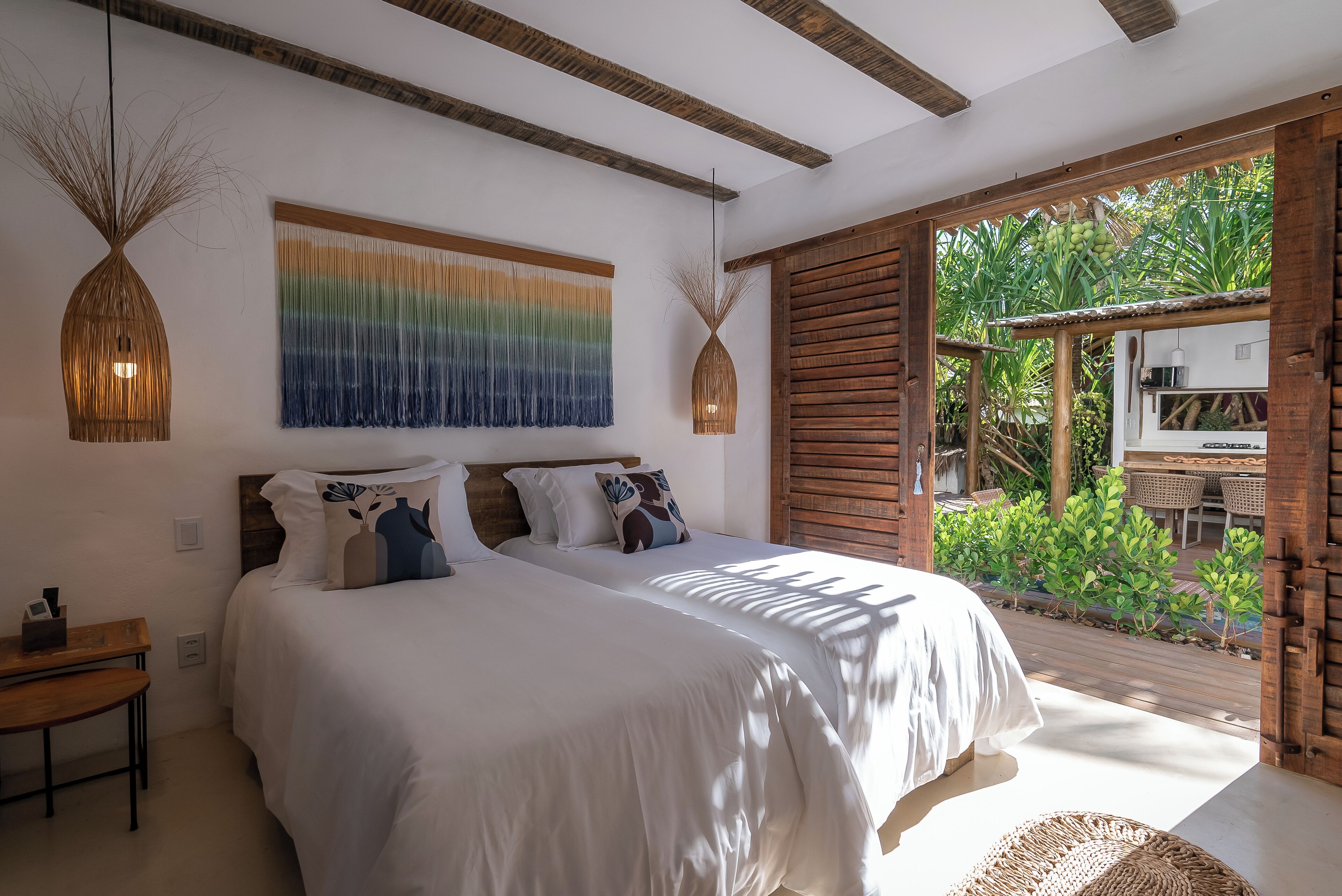 Un dormitorio con dos camas, techo de madera, un ventanal y vista a zonas verdes.
