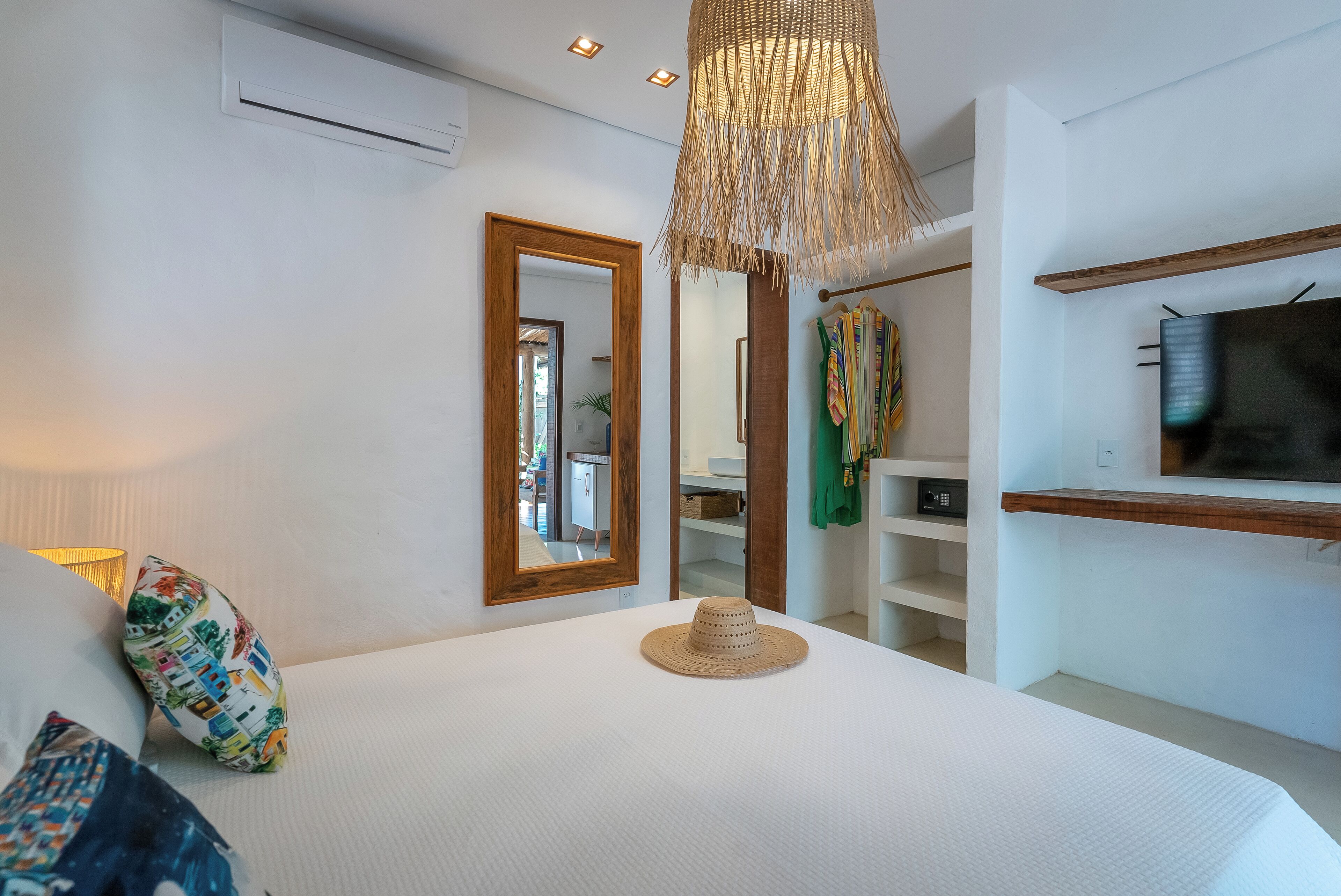 A bedroom with a large bed, a mirror, a wardrobe, and a television.