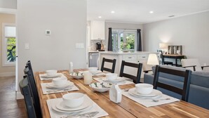 Een eetruimte met een houten tafel gedekt voor vier personen, witte borden, kommen en bestek.