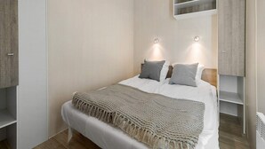A modern bedroom with a bed, bedside tables, and built-in shelving. - 6 Person Holiday Park Home in Hesselager (Hesselager)