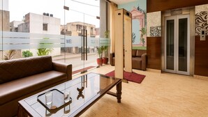 A modern lobby with a glass coffee table, leather sofa, and a mural on the wall.
